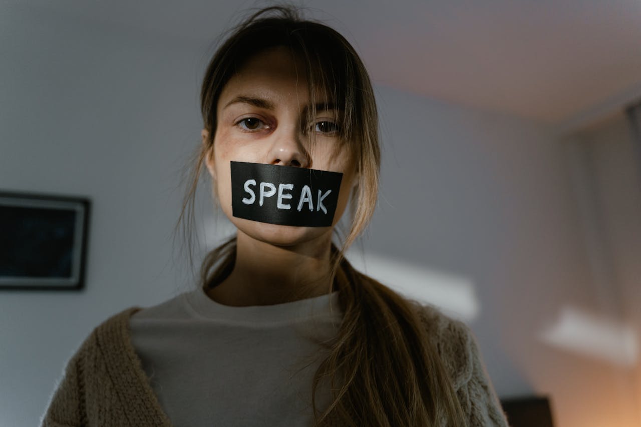 heros-img Woman with 'speak' tape over mouth.